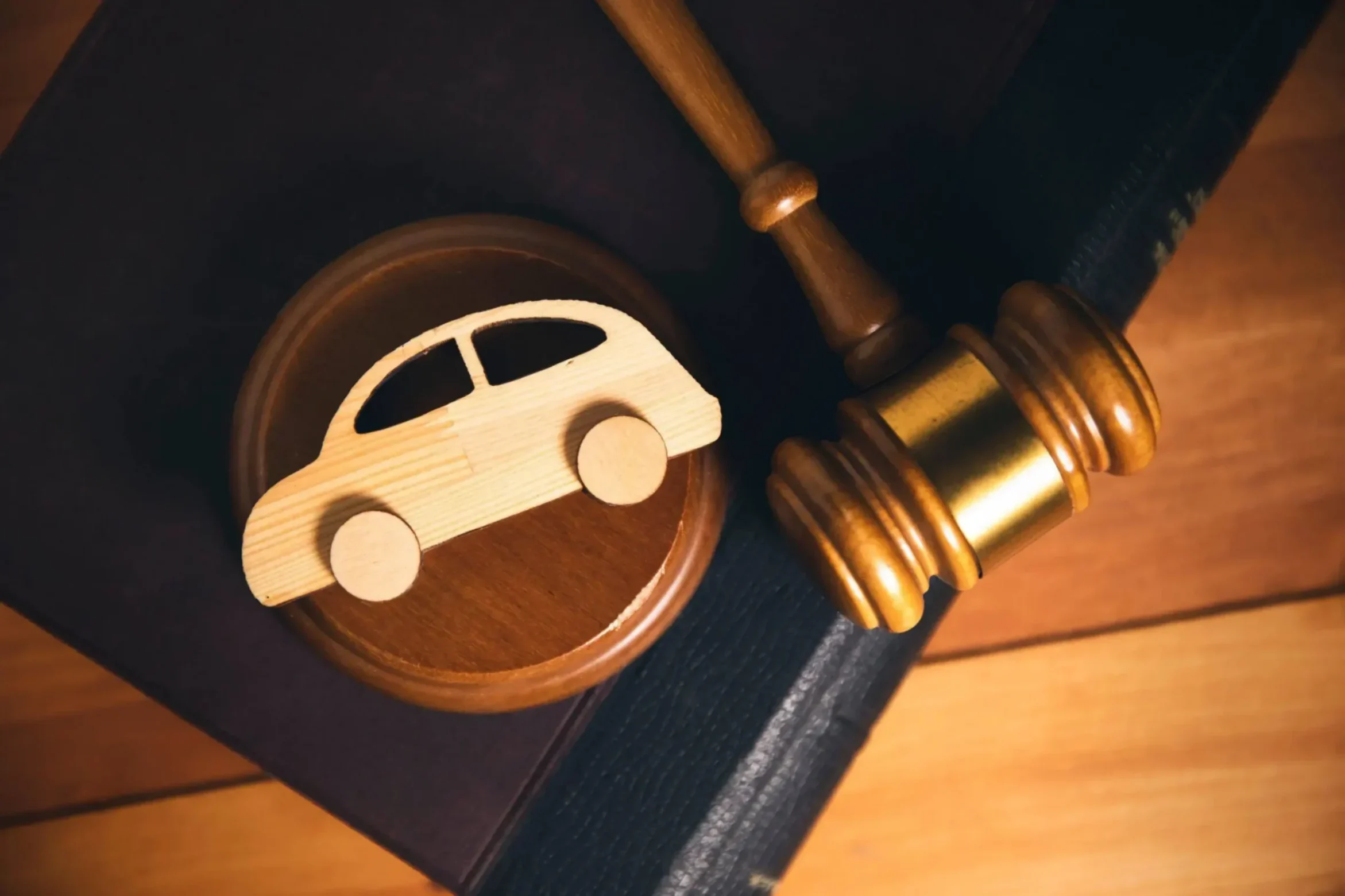 Wooden car symbol resting on a legal book beside a judge’s gavel, representing a car accident lawsuit in Arizona.